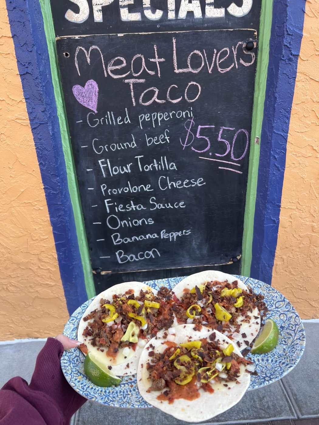 Meat Lovers Taco in front of the specials board
